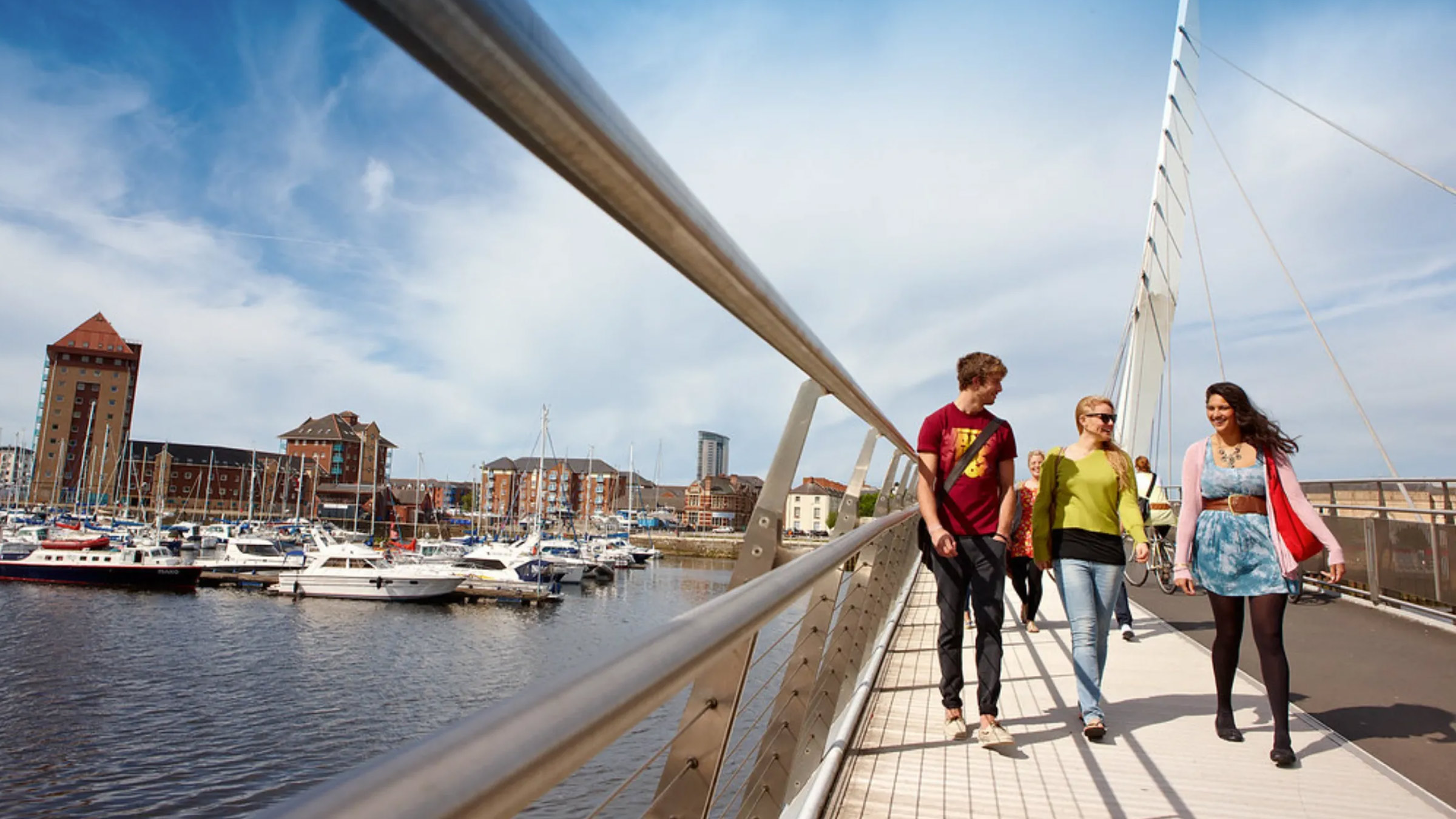Students walking on a footbridge in Swansea.