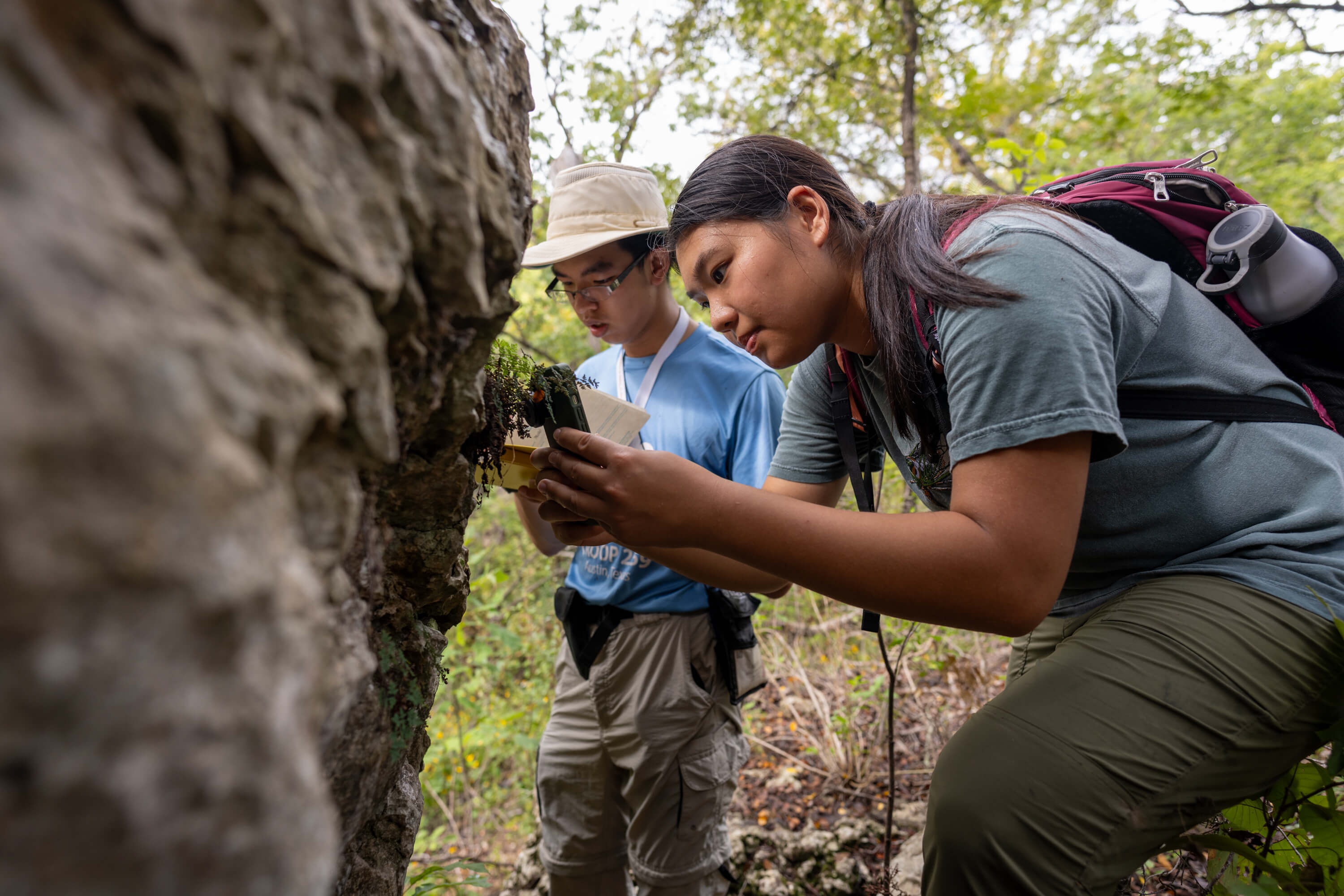 Male and female students studying a rock